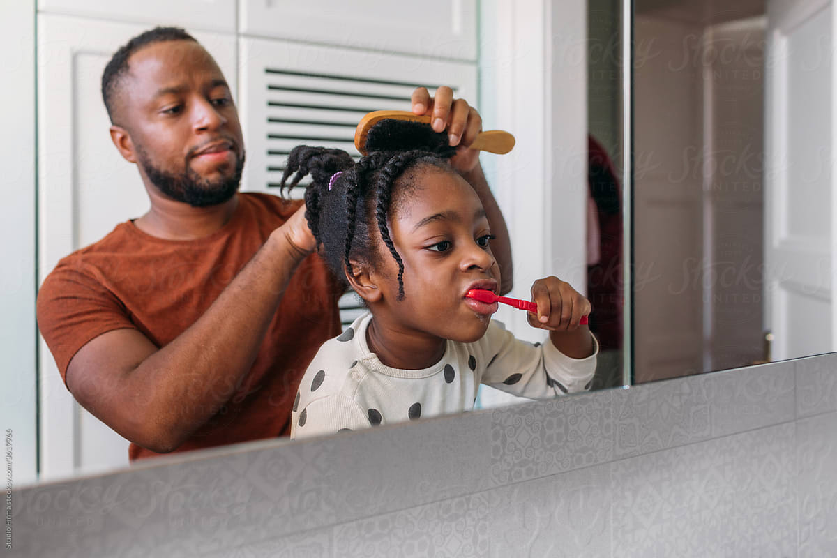 A handsome man helping his little girl in the bathroom